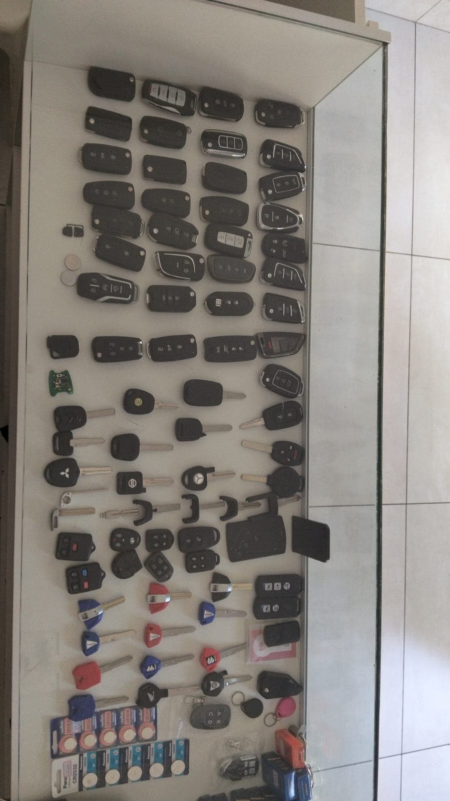 Vitrine da loja com dezenas de chaves e controles de carro, chaves canivete e de moto, e baterias